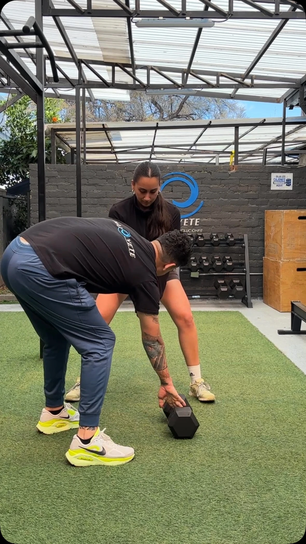 Entrenador guiando un ejercicio con mancuerna en Muévete